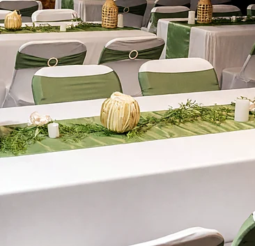 Table centrepieces with flowers and candles on a green runner at an event set by Ponnus Caters & Events