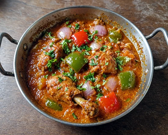 Chicken kadai curry with bell peppers and onion in a steel kadai